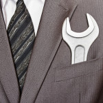 Big industrial spanner in businessman suit pocket